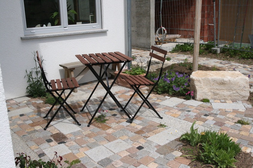 Kleiner Sitzplatz mit gemischtem Pflaster, dass für kleine betretbare Polsterstauden wie  Thymian, Sternmoos oder römische Kamille unterbrochen wurde. (München)