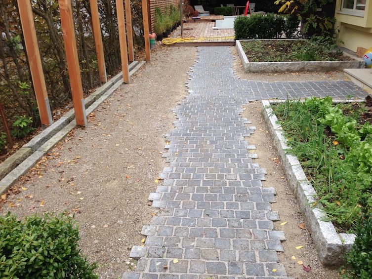 Weg aus dunklem Granit mit ausgefransten Rändern, wassergebundene Decke und mit Granit eingefasste Gemüsebeete 20cm erhöht. (München - Solln)