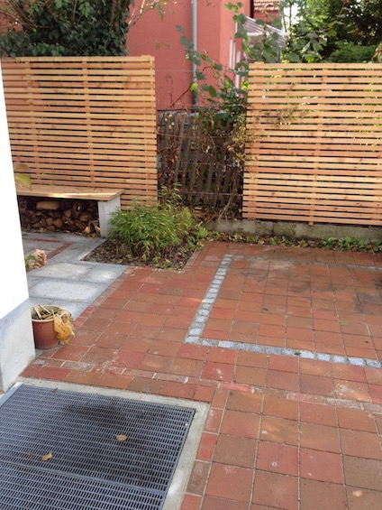 Sichtschutz aus waagrechter Holzlattung mit unregelmässigen Unterbrechungen, die mit Edelstahlseilen verbunden und Kletterpflanzen berankt wurden. (München)