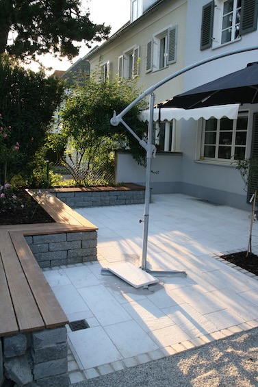 Lounge Terrasse mit Sitzmauer aus dunklem Granit, Holzauflage aus Bangkirai und Belag aus Rauriser Marmor. (München)