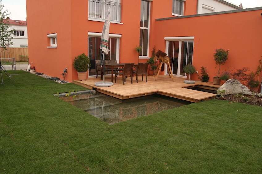 Holzdeck, Wasser und Steg übers Wasser auf den Rasen (Poing bei München)