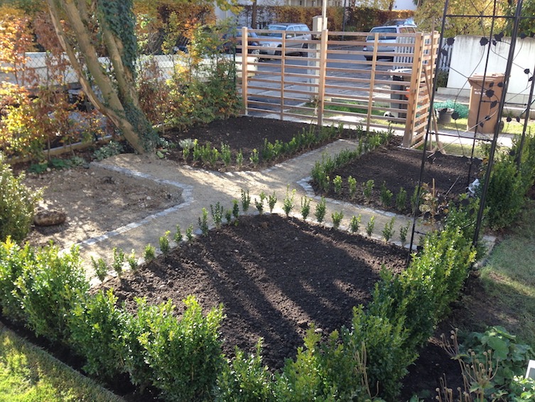 Klassischer Bauerngarten mit Wegekreuz und Einfassung aus Buchs. Ein Viertel der Pflanzliche wird befestigt als kleiner Sitzplatz zum Verweilen. (München)