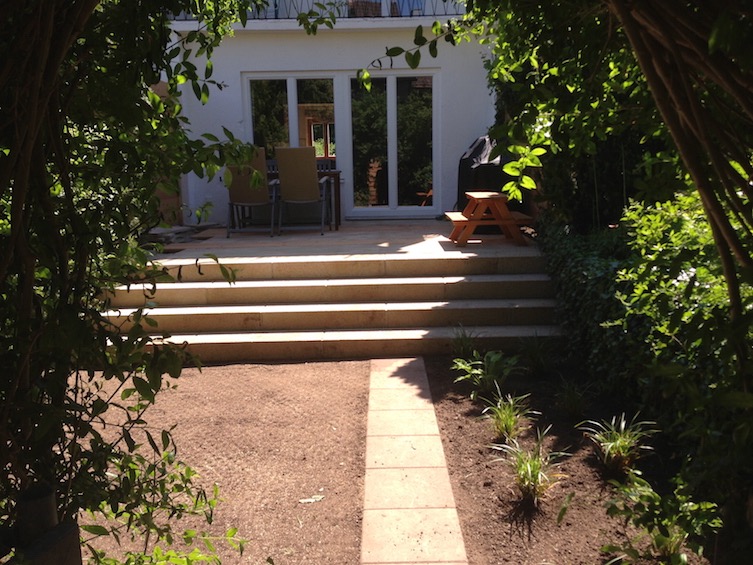 Garten, der mit einer Treppe aus Blockstufen über die ganze Breite großzügiger wirkt. (München)